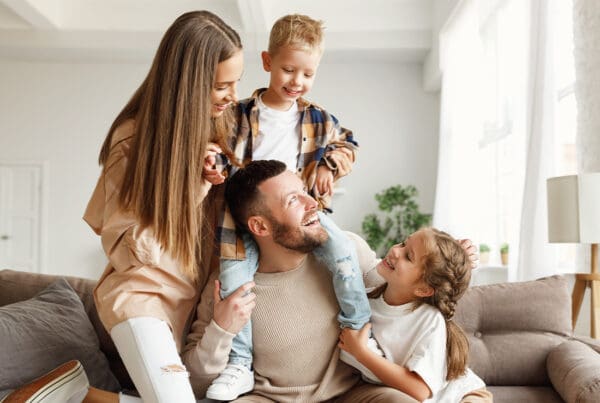 Personal Insurance - Happy Family With Mother and Father and Kids Having Fun at Home on Couch