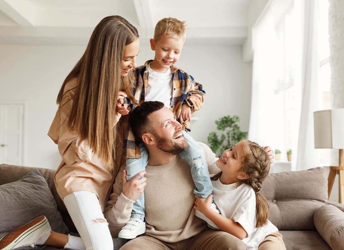 Personal Insurance - Happy Family With Mother and Father and Kids Having Fun at Home on Couch
